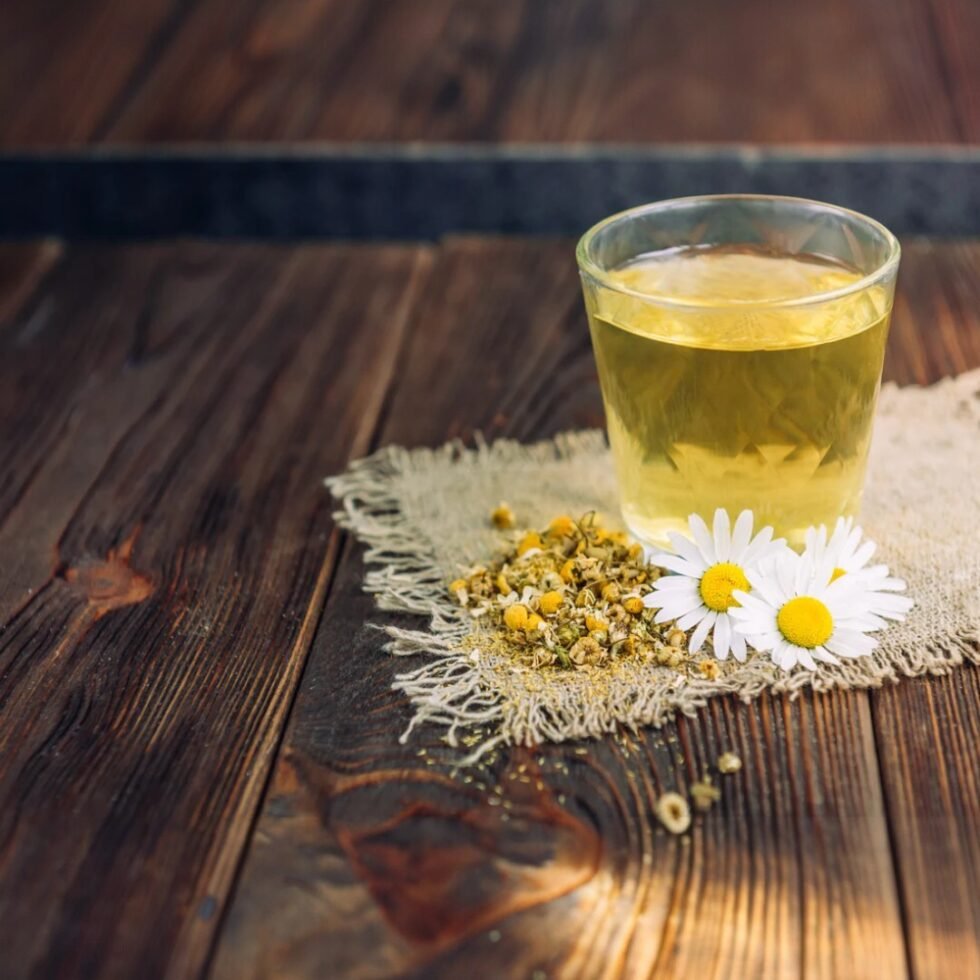 Dried chamomile flowers in a pouch and cup of herbal tea, organically grown and hand-packed in the hills of Himachal – calming, aromatic, and caffeine-free.