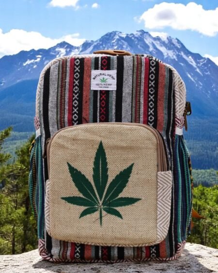 Handcrafted backpack made from cotton and hemp fabric with green hemp leaf print, featuring Himachali tribal design, placed on a rustic wooden table in the Himalayan outdoors