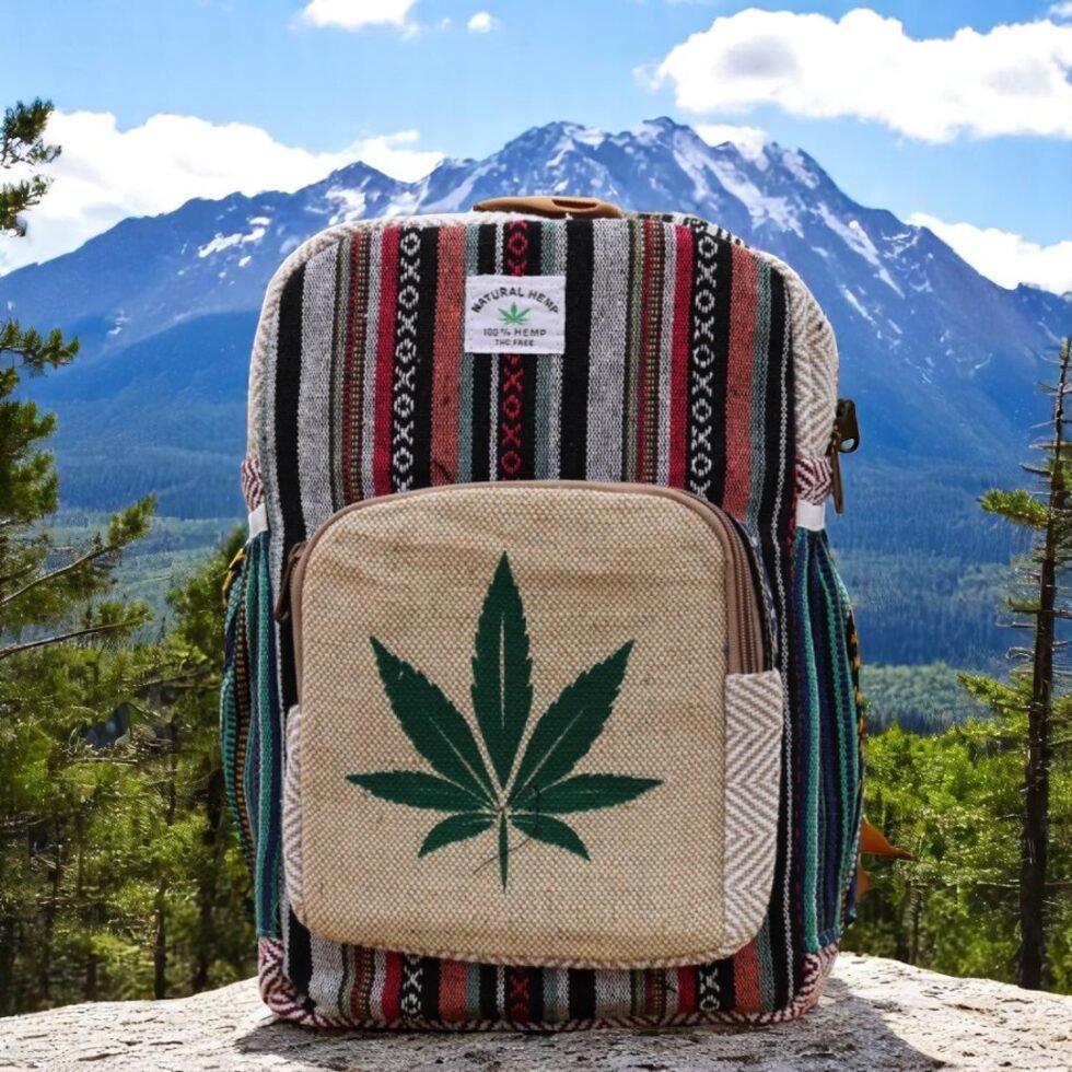Handcrafted backpack made from cotton and hemp fabric with green hemp leaf print, featuring Himachali tribal design, placed on a rustic wooden table in the Himalayan outdoors