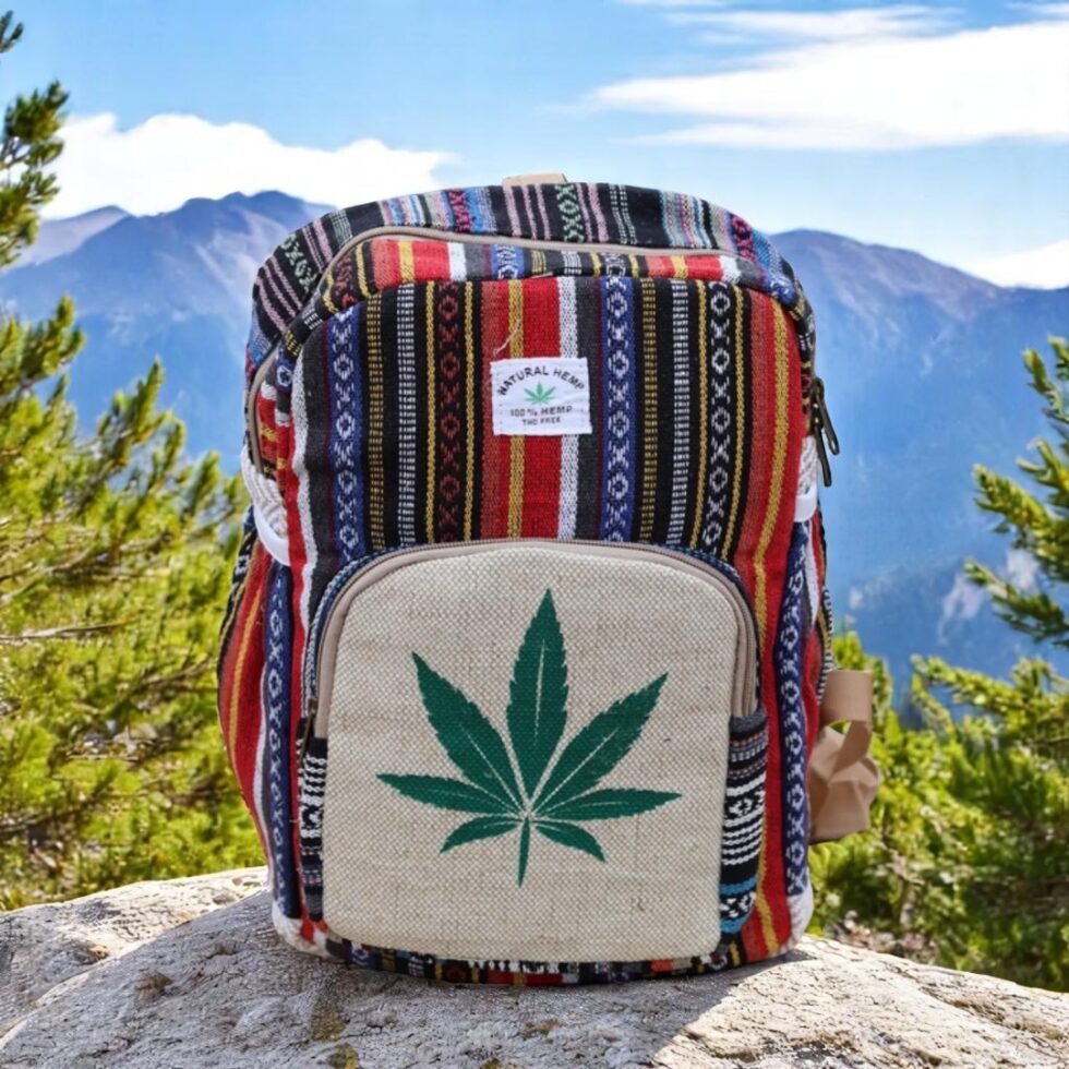 Handcrafted backpack made from cotton and hemp fabric with green hemp leaf print, featuring Himachali tribal design, placed on a rustic wooden table in the Himalayan outdoors