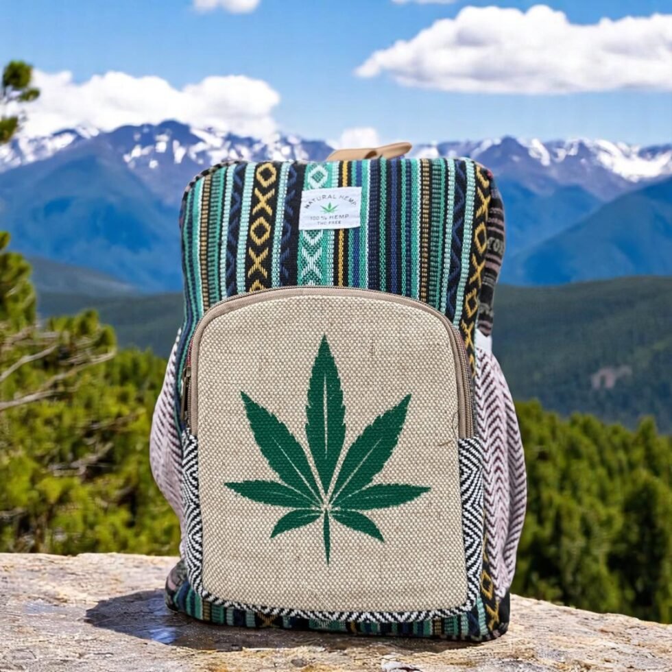 Handcrafted backpack made from cotton and hemp fabric with green hemp leaf print, featuring Himachali tribal design, placed on a rustic wooden table in the Himalayan outdoors