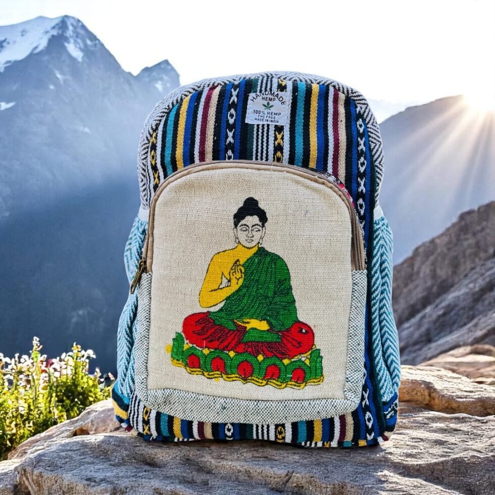 Handmade hemp and cotton backpack with Buddha art print, featuring tribal Himachali fabric details, placed in front of a natural mountain landscape from Kasol, Himachal