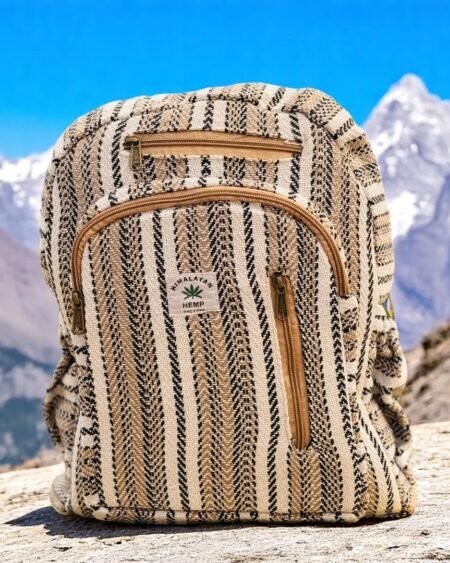 Handmade Himalayan hemp backpack with tribal stripes placed on a rock with snow-capped Himalayan mountains in the background.