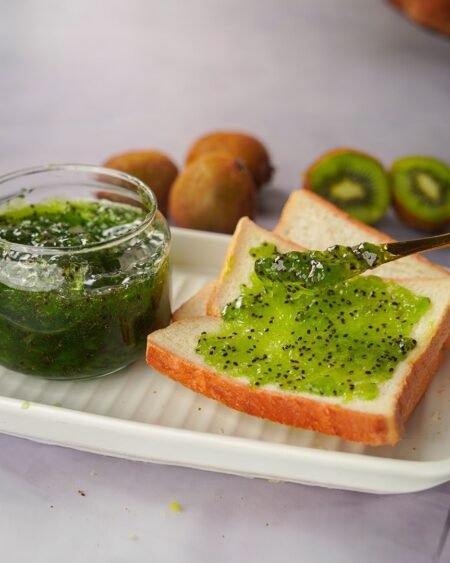 Homemade kiwi jam in a glass jar, made from fresh Himalayan kiwis, with a rustic label and wooden spoon beside it – a natural and fruity delicacy from Himachal Pradesh 5- Himachalbox.com